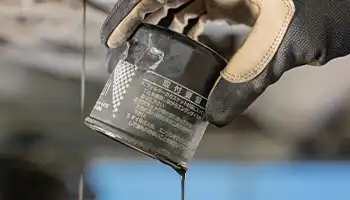 Hand holding oil filter dripping oil