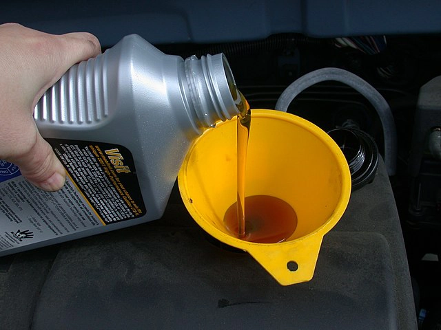 Oil being poured into yellow funnel